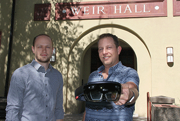 Ben Katko (right) and John Estry show the Microsoft HoloLens that they are using to create augmented reality tools for use in industry in the Senior Design Clinic. 